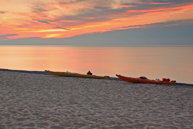 kayaks pulled up on the beach at sunset